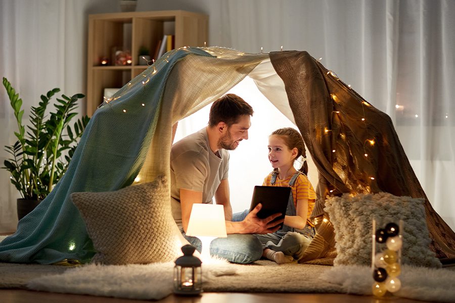 Blog - Happy Father and Daughter with Tablet in Child Play Tent at Night Inside the Home